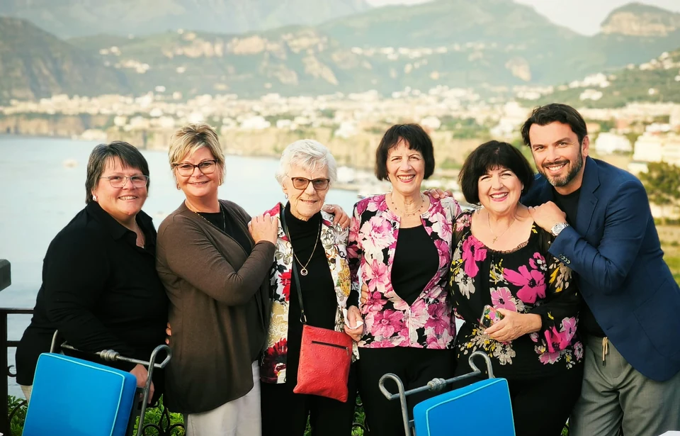 Sasha Rojnik with guests on a terrace overlooking the coast